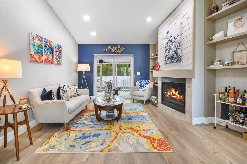 A living room features a fireplace, a blue accent wall, and a colorful area rug — 851 3RD AVENUE S, TIERRA VERDE, FL