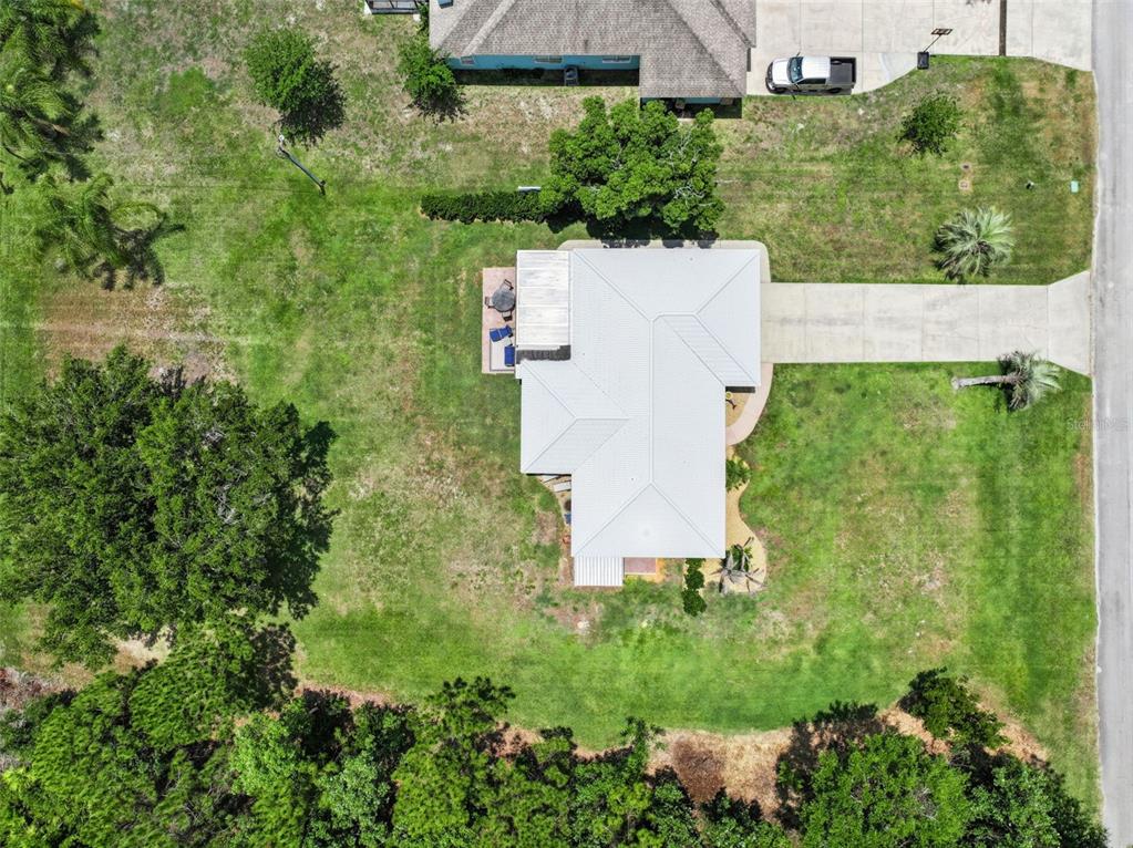 An aerial view shows a house with a light-colored roof, driveway, and surrounding yard — 7651 LIMONIA DRIVE, INDIAN LAKE ESTATES, FL
