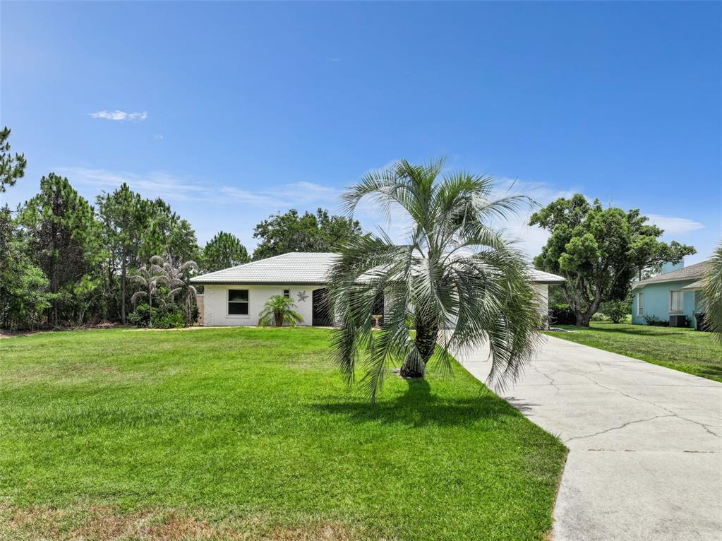 A single-story white house with a tiled roof sits on a large, grassy lot — 7651 LIMONIA DRIVE, INDIAN LAKE ESTATES, FL