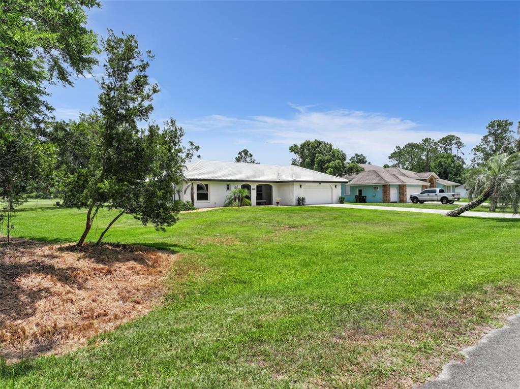 A single-story house with a white exterior, a tiled roof, and a large front lawn — 7651 LIMONIA DRIVE, INDIAN LAKE ESTATES, FL
