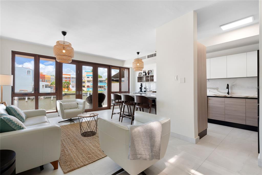 A modern living room and kitchen area with white furniture, a jute rug, and waterfront views — 260 HARBOUR DRIVE UNIT 13, HUMACAO, PR