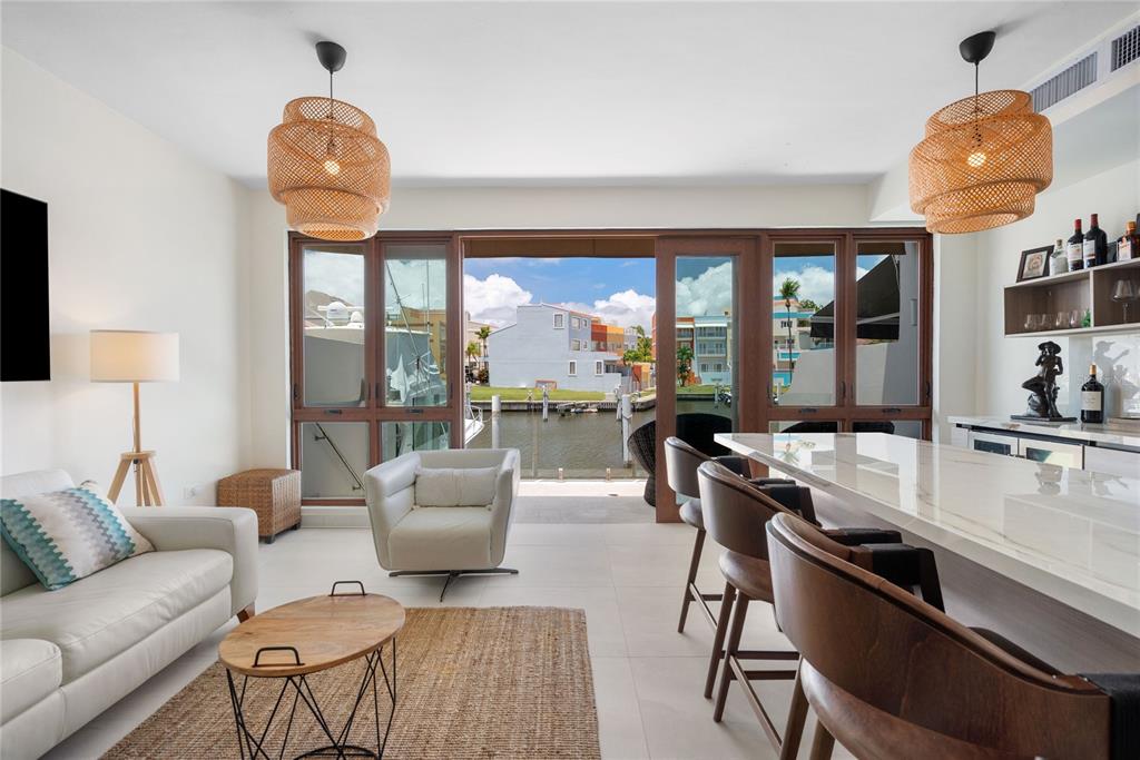 A living room with a kitchen island, wicker pendant lights, and a view of a canal — 260 HARBOUR DRIVE UNIT 13, HUMACAO, PR