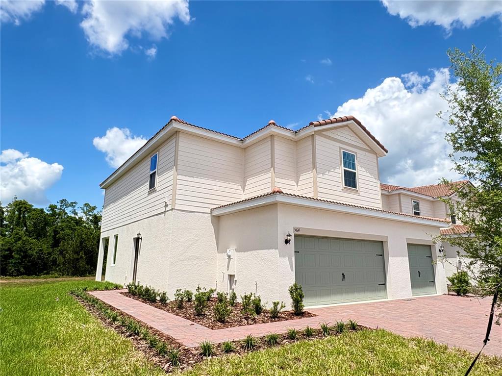 A two-story house with beige siding, a stucco base, and a two-car garage — 564 BAY LEAF DRIVE, POINCIANA, FL