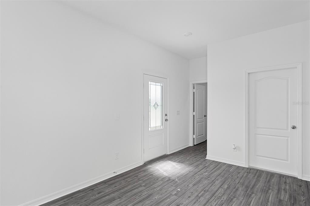 An interior view of a room with white walls, gray wood-look flooring, and two doors — 564 BAY LEAF DRIVE, POINCIANA, FL