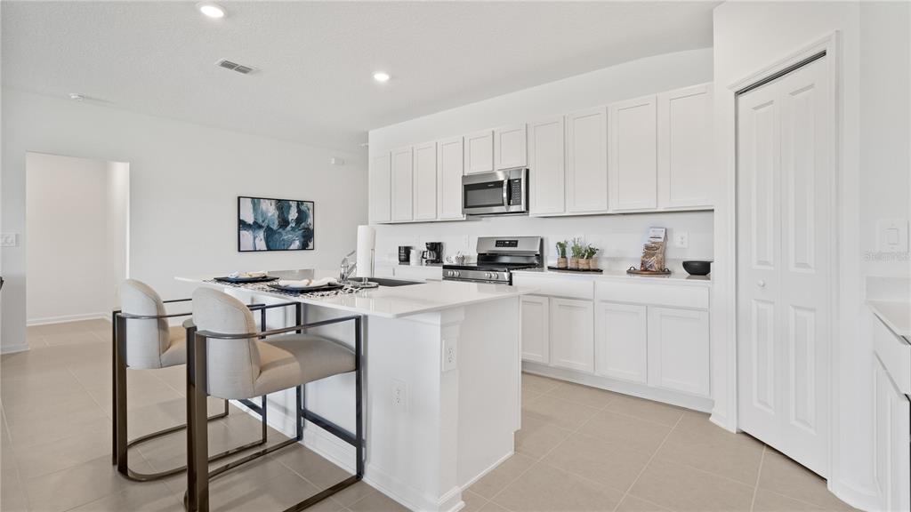 A modern kitchen features white cabinets, stainless steel appliances, and a large central island — 1950 PINE MEADOWS GOLFCOURSE ROAD, EUSTIS, FL
