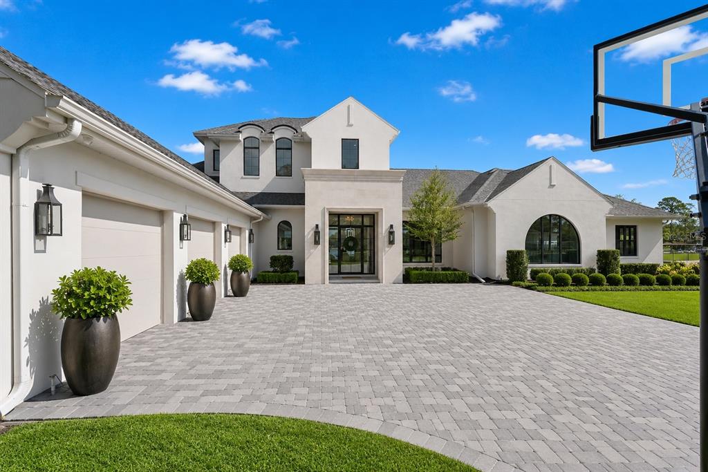 A modern white house with a paved driveway, three-car garage, and a basketball hoop — 320 EVANSDALE ROAD, LAKE MARY, FL