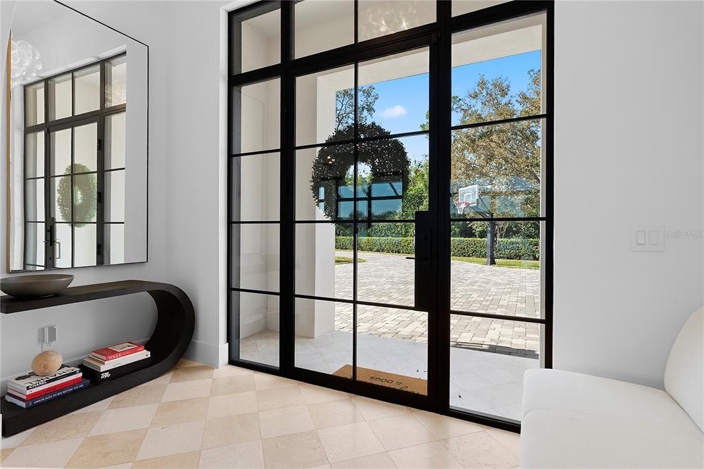 A modern entryway features a black-framed glass door, a curved console table, and light tile flooring — 320 EVANSDALE ROAD, LAKE MARY, FL