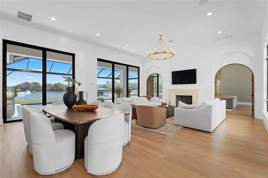 An open-concept living and dining area features light wood floors, white walls, and lake views — 320 EVANSDALE ROAD, LAKE MARY, FL
