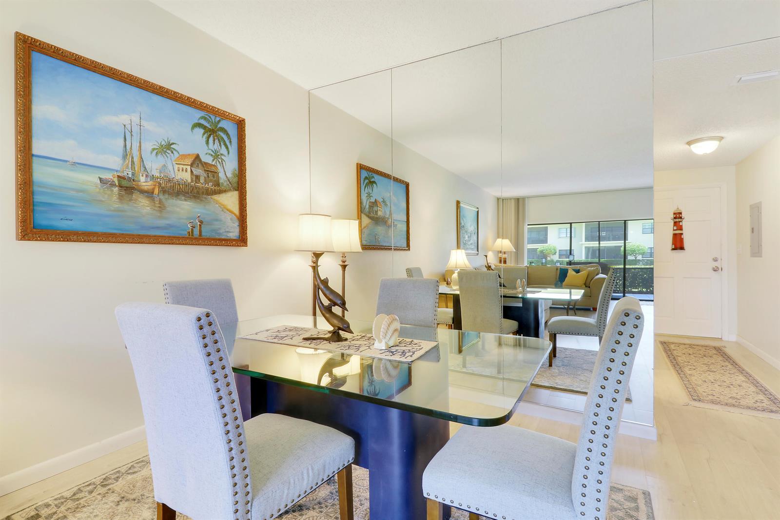 A dining area features a glass table, upholstered chairs, and a large wall-to-wall mirror — 275 S Beach Road, Tequesta FL 33469, TEQUESTA, FL