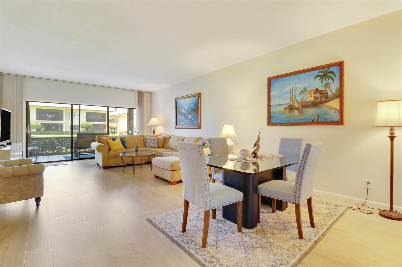 A living and dining area with light wood floors, a sectional sofa, and a glass-topped table — 275 S Beach Road, Tequesta FL 33469, TEQUESTA, FL