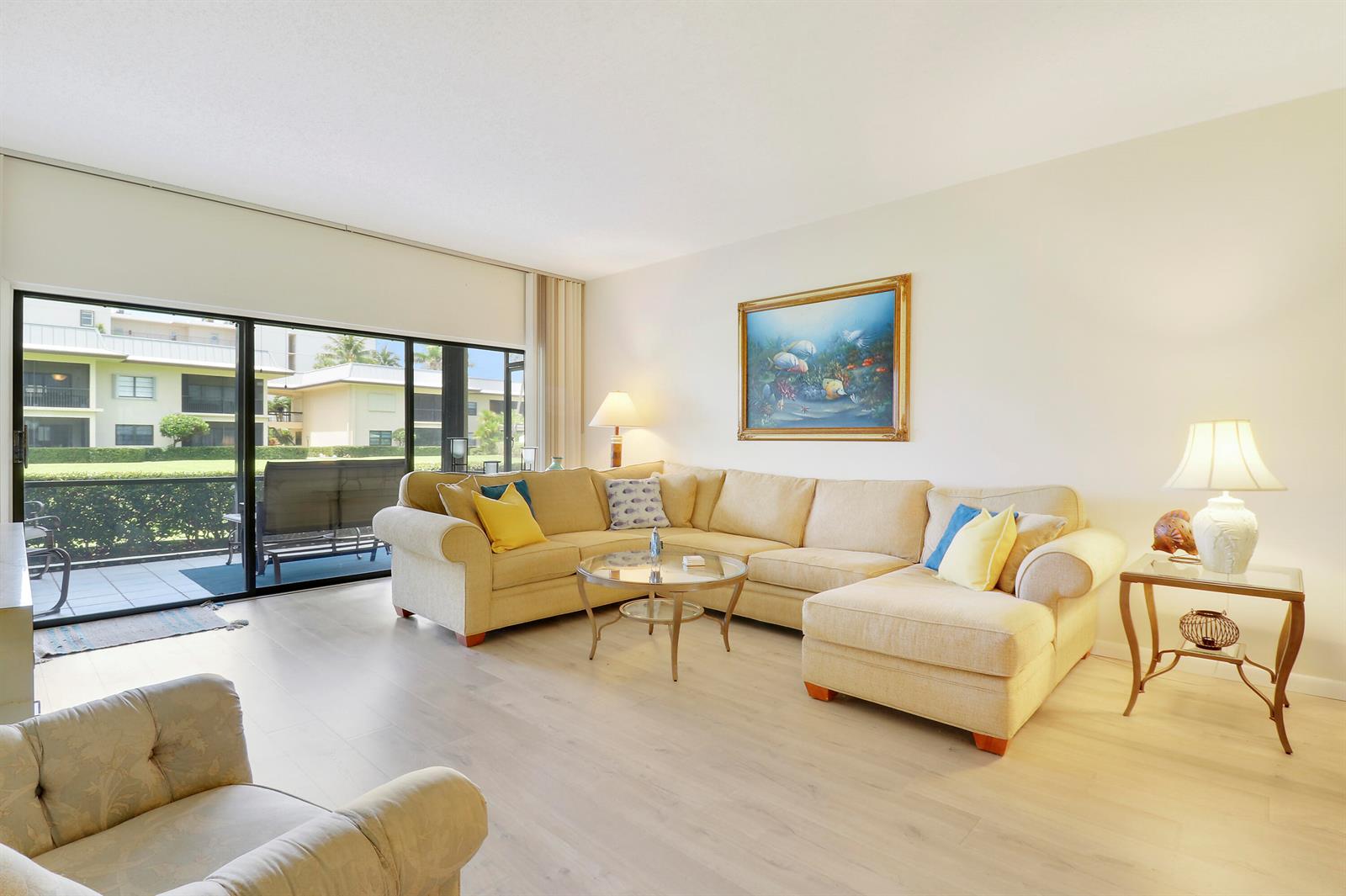 A living room features a beige sectional sofa, a glass coffee table, and sliding glass doors — 275 S Beach Road, Tequesta FL 33469, TEQUESTA, FL