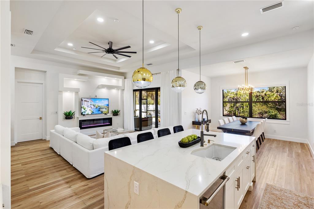An open-concept living room and kitchen featuring a white island, fireplace, and dining area — 2470 ABBOTSFORD STREET, NORTH PORT, FL