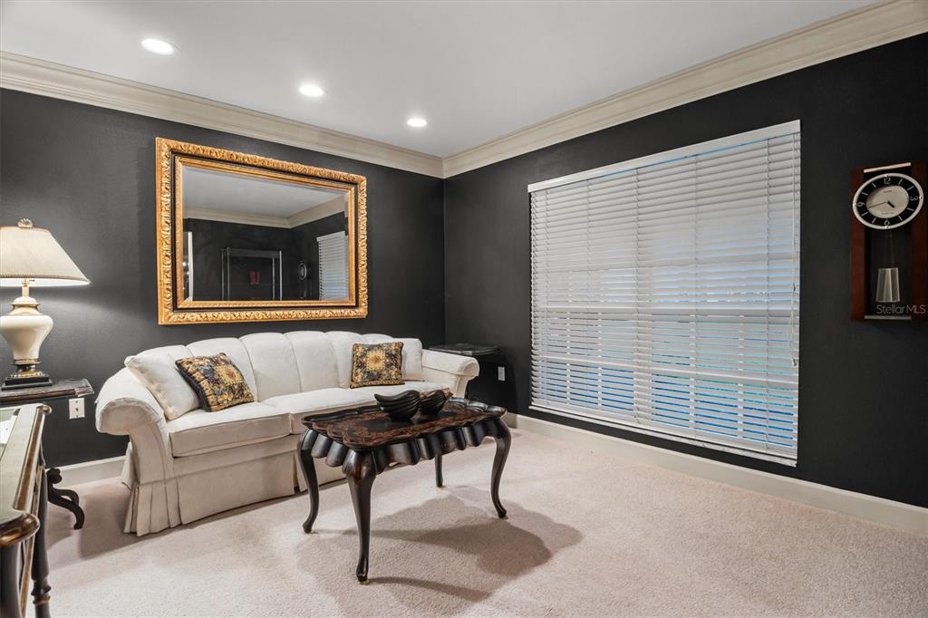 A living room features dark walls, a white sofa, a gold-framed mirror, and a wall clock — 1142 LONGWOOD OAKS BOULEVARD, LAKELAND, FL