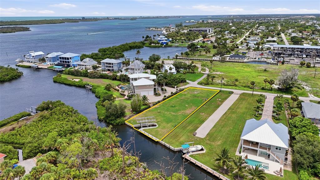 An aerial view shows a vacant waterfront lot outlined in yellow next to a canal — 1947 WISCONSIN AVENUE, ENGLEWOOD, FL