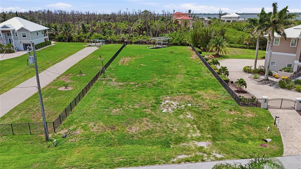 An aerial view shows a vacant, fenced grassy lot situated between two residential houses — 1947 WISCONSIN AVENUE, ENGLEWOOD, FL