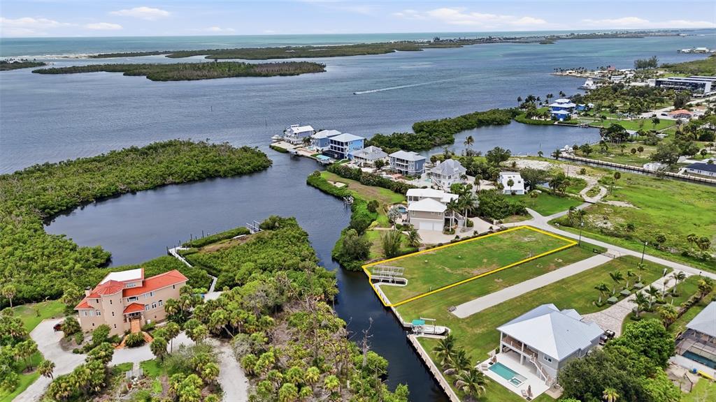 An aerial view shows a vacant waterfront lot outlined in yellow near several residential homes — 1947 WISCONSIN AVENUE, ENGLEWOOD, FL