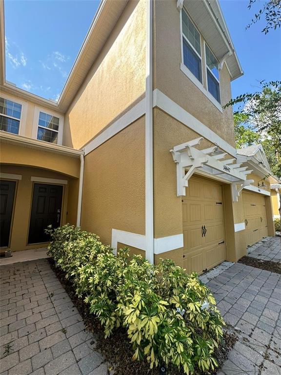 A two-story yellow stucco townhouse features a front entrance, a garage, and a landscaped bush — 14442 DESERT HAVEN STREET UNIT 4305, WINDERMERE, FL