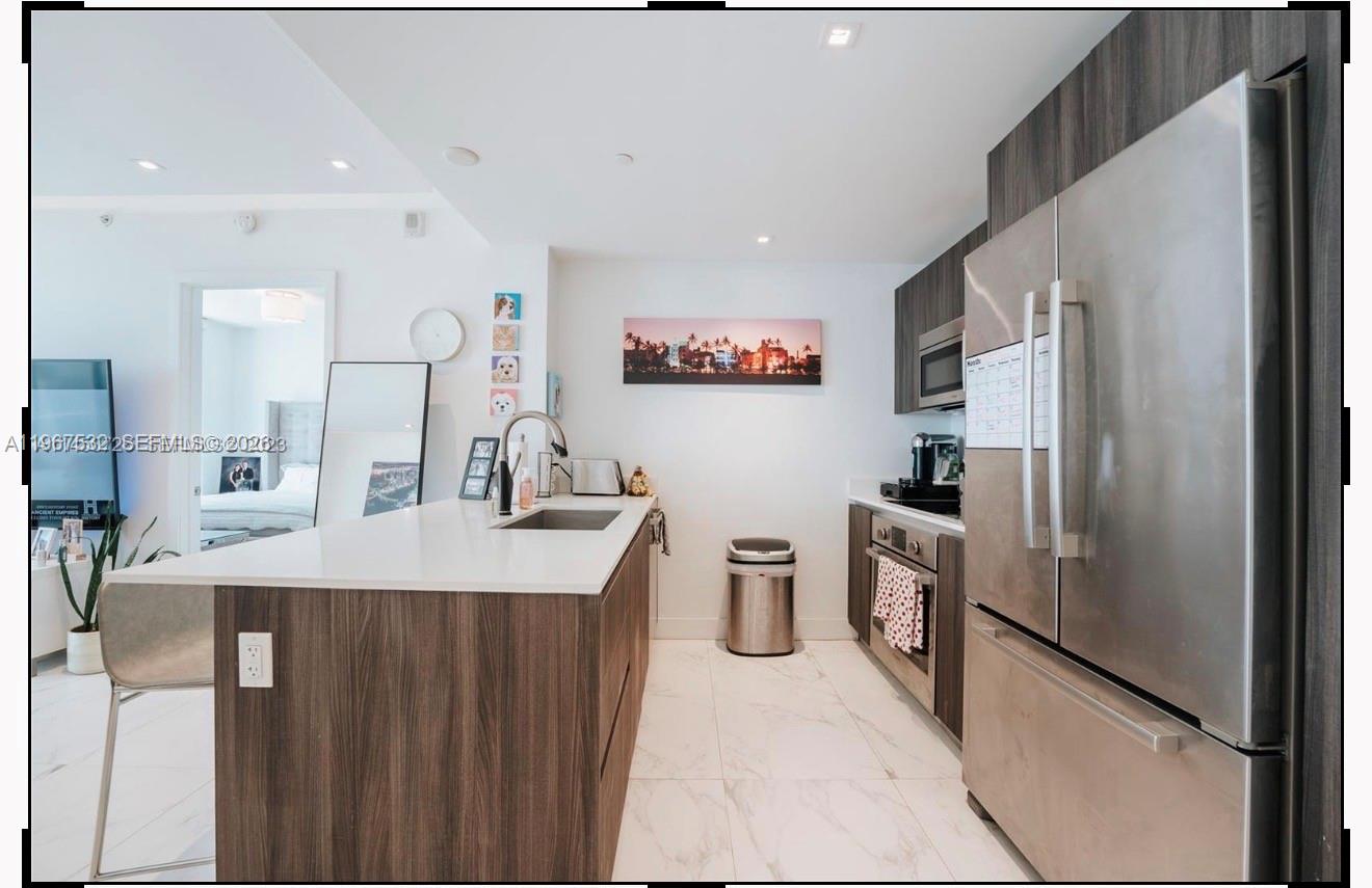 A modern kitchen features a white island, stainless steel appliances, and wood-toned cabinetry — 488 NE 18th St # 4304, Miami FL 33132, MIAMI, FL