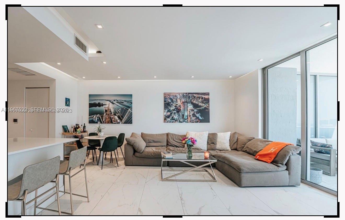 A modern living room features a large sectional sofa, dining area, and floor-to-ceiling windows — 488 NE 18th St # 4304, Miami FL 33132, MIAMI, FL