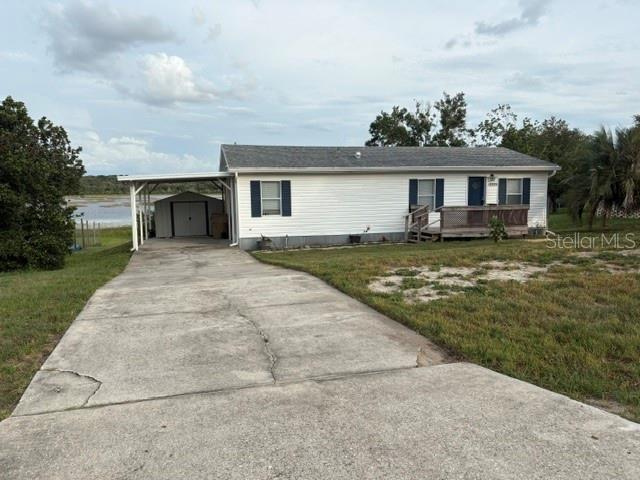 A carport with a storage shed sits beside a house overlooking a body of water — 13225 PLUM LAKE CIRCLE, MINNEOLA, FL