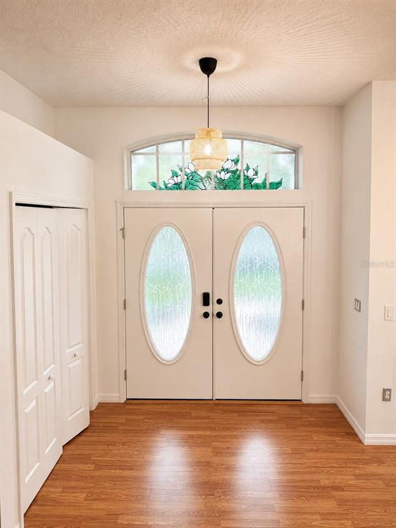 An entryway features double doors with oval glass inserts, a stained-glass transom, and wood flooring — 12716 BALSAM AVENUE, HUDSON, FL