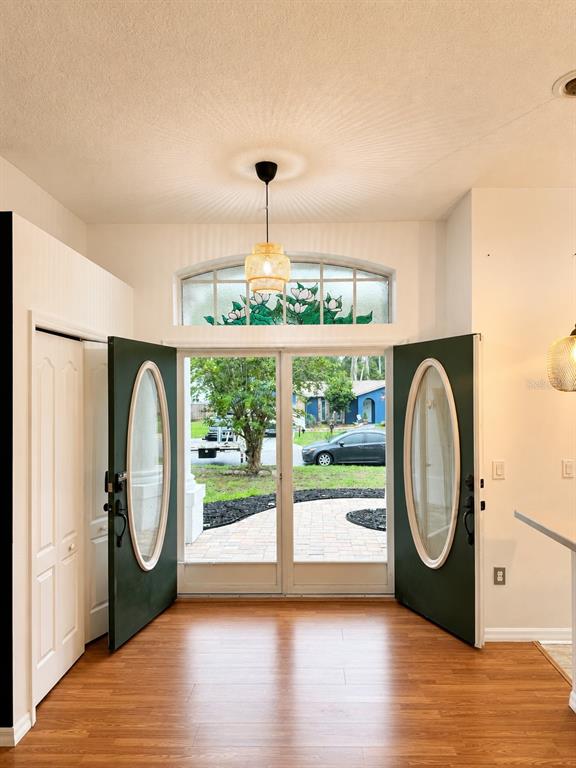 An entryway features double green doors with oval glass inserts, wood flooring, and a transom window — 12716 BALSAM AVENUE, HUDSON, FL