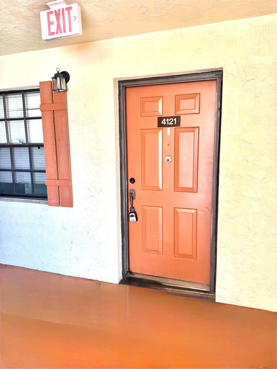 An exterior view shows an orange apartment door numbered 4121 next to a window — 4121 Oak Terrace Drive, FL 33463, FL
