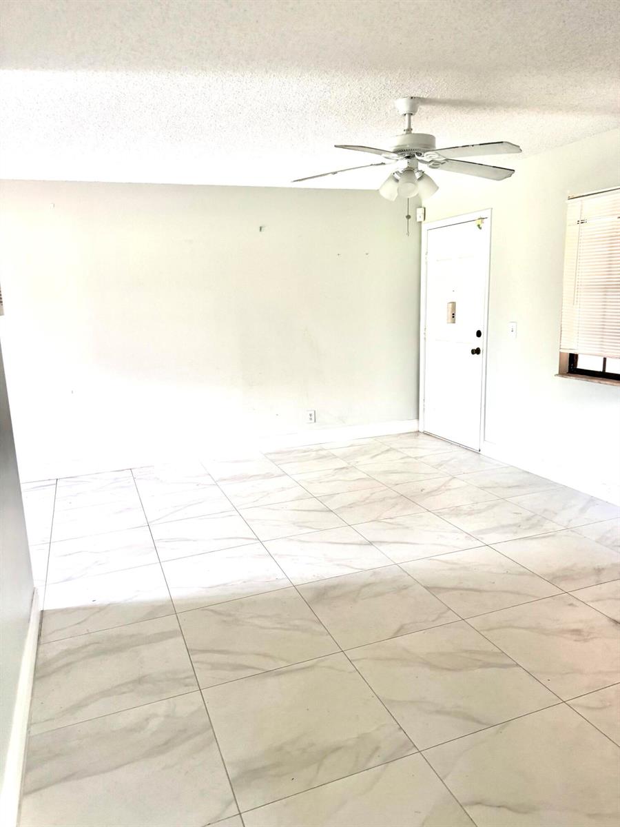 An empty room features white marble-look tile flooring, a ceiling fan, and a white door — 4121 Oak Terrace Drive, FL 33463, FL