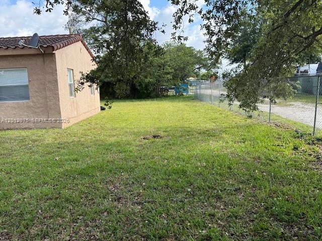 A side view of a tan stucco house with a tiled roof and a grassy yard — 6013 SW 34th St, Miramar FL 33023, MIRAMAR, FL