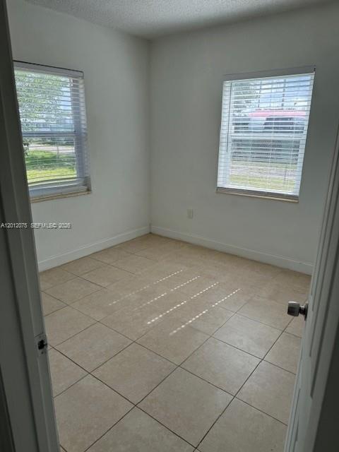 An empty room features light-colored tile flooring, white walls, and two windows with blinds — 6013 SW 34th St, Miramar FL 33023, MIRAMAR, FL