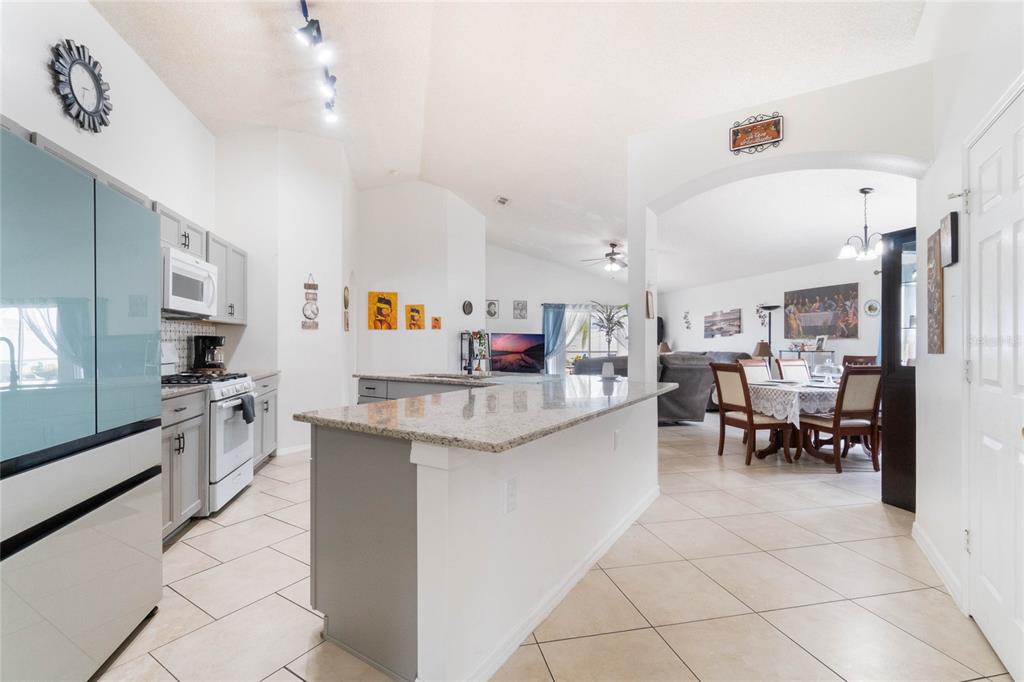 A kitchen with gray cabinets and a granite island opens into a dining area — 640 LADY DIANA DRIVE, DAVENPORT, FL