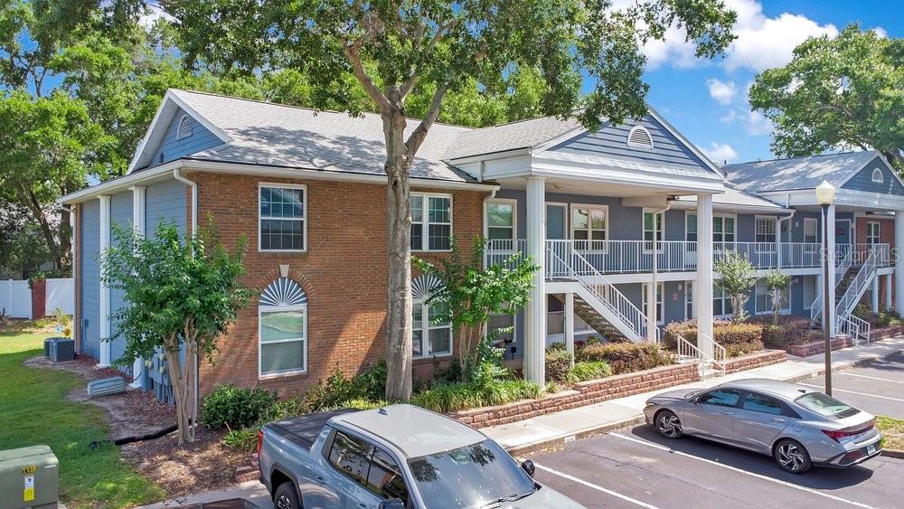 A two-story apartment building with brick and blue siding features an exterior staircase and parking — 5449 LAKE MARGARET DRIVE UNIT 86, ORLANDO, FL