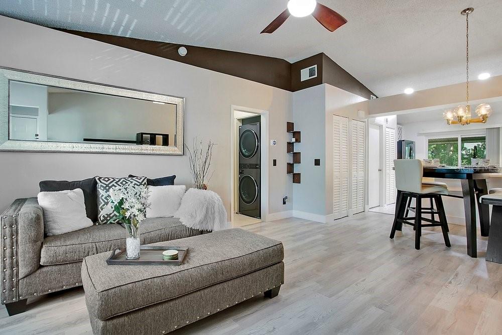A living room with light wood floors, a grey sofa, and an adjacent dining area — 5449 LAKE MARGARET DRIVE UNIT 86, ORLANDO, FL