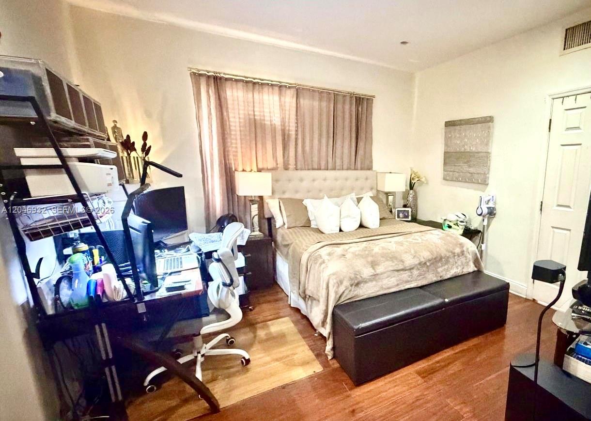 A bedroom features a bed with a tufted headboard, a desk, and wood flooring — 750 Jefferson Ave # 4, Miami Beach FL 33139, MIAMI BEACH, FL