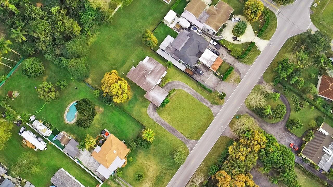 An aerial view shows several houses with driveways, green lawns, and trees along a road — 13945 N Miami Avenue, Miami FL 33168, MIAMI, FL