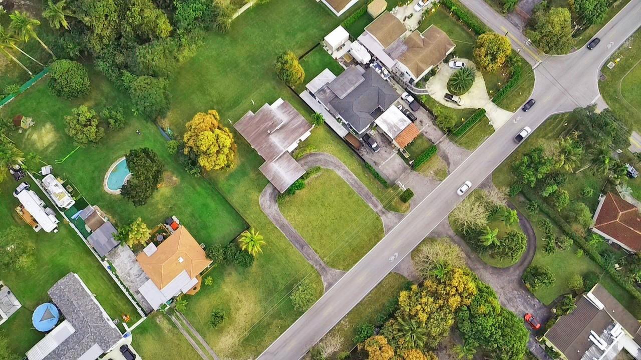 An aerial view shows several suburban houses with driveways, swimming pools, and trees along a road — 13945 N Miami Avenue, Miami FL 33168, MIAMI, FL