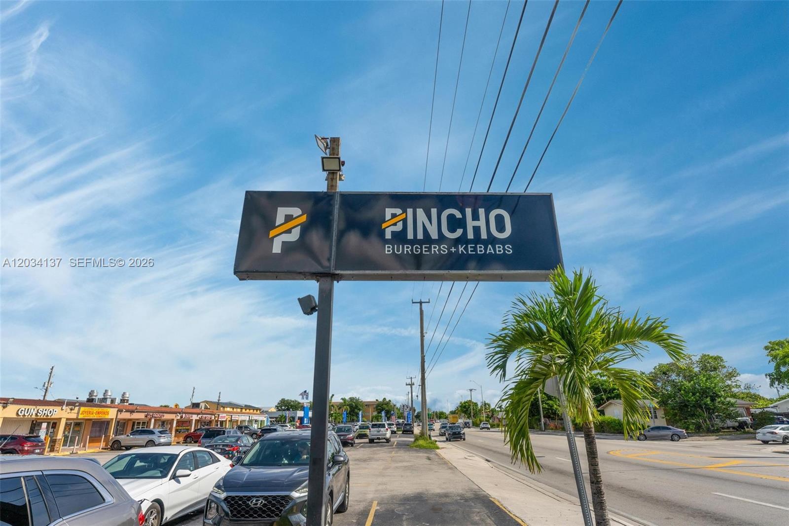 A sign for Pincho Burgers and Kebabs stands in a parking lot near a road — 4950 W 12th Ave, Hialeah FL 33012, HIALEAH, FL