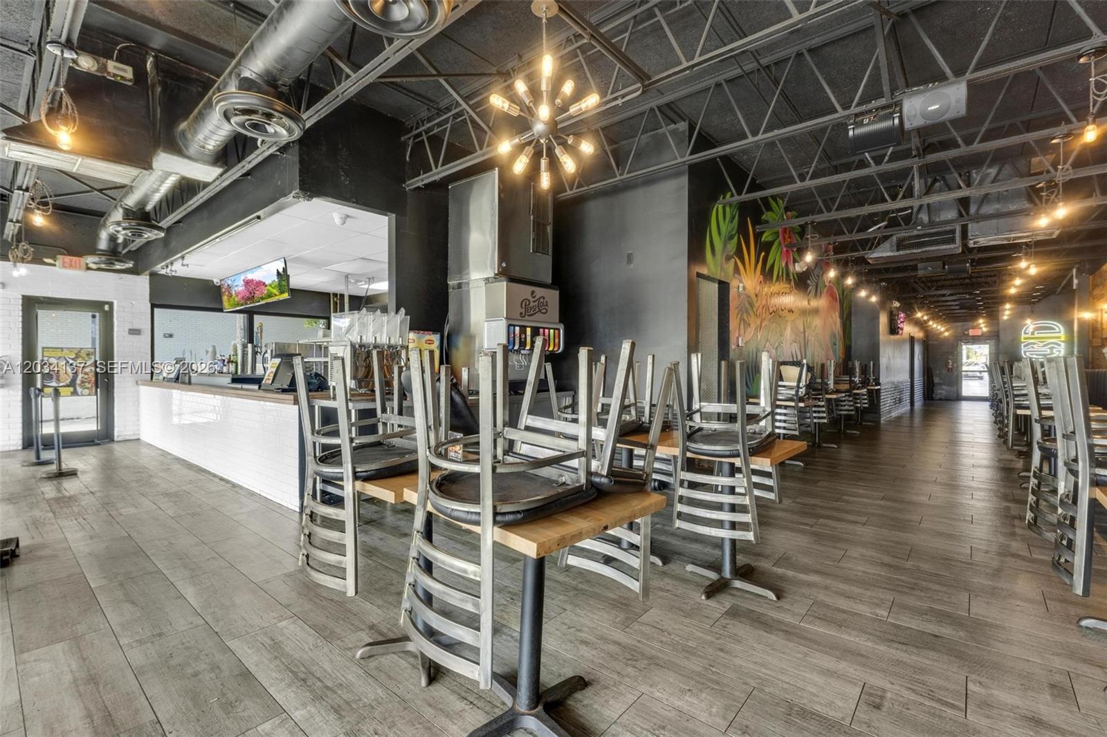 A restaurant interior features metal chairs stacked on wooden tables under an exposed ceiling — 4950 W 12th Ave, Hialeah FL 33012, HIALEAH, FL