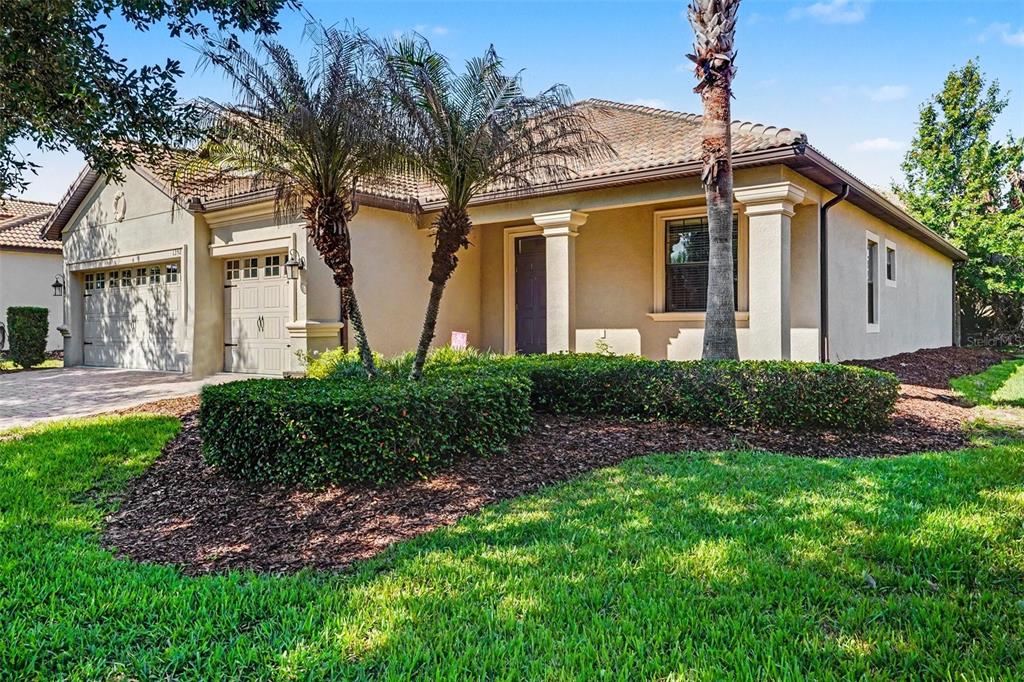 A single-story stucco house with a tile roof, two-car garage, and landscaped front yard — 1392 PALMETTO DUNES STREET, DAVENPORT, FL