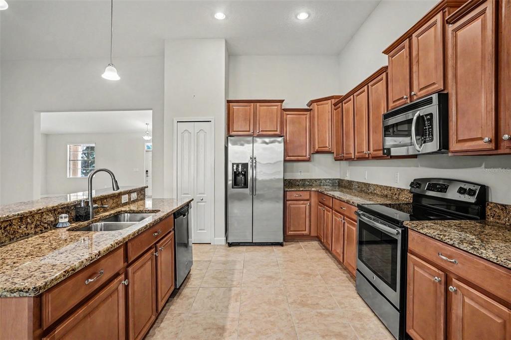A kitchen with wood cabinets, granite countertops, stainless steel appliances, and tile flooring — 1392 PALMETTO DUNES STREET, DAVENPORT, FL