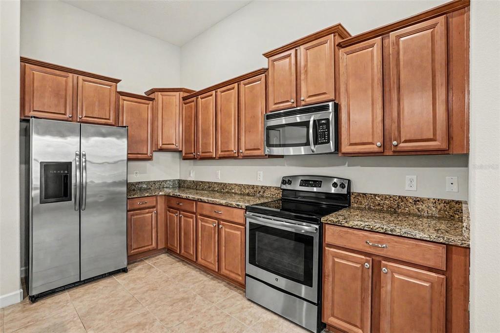 A kitchen with wood cabinets, granite countertops, and stainless steel appliances — 1392 PALMETTO DUNES STREET, DAVENPORT, FL