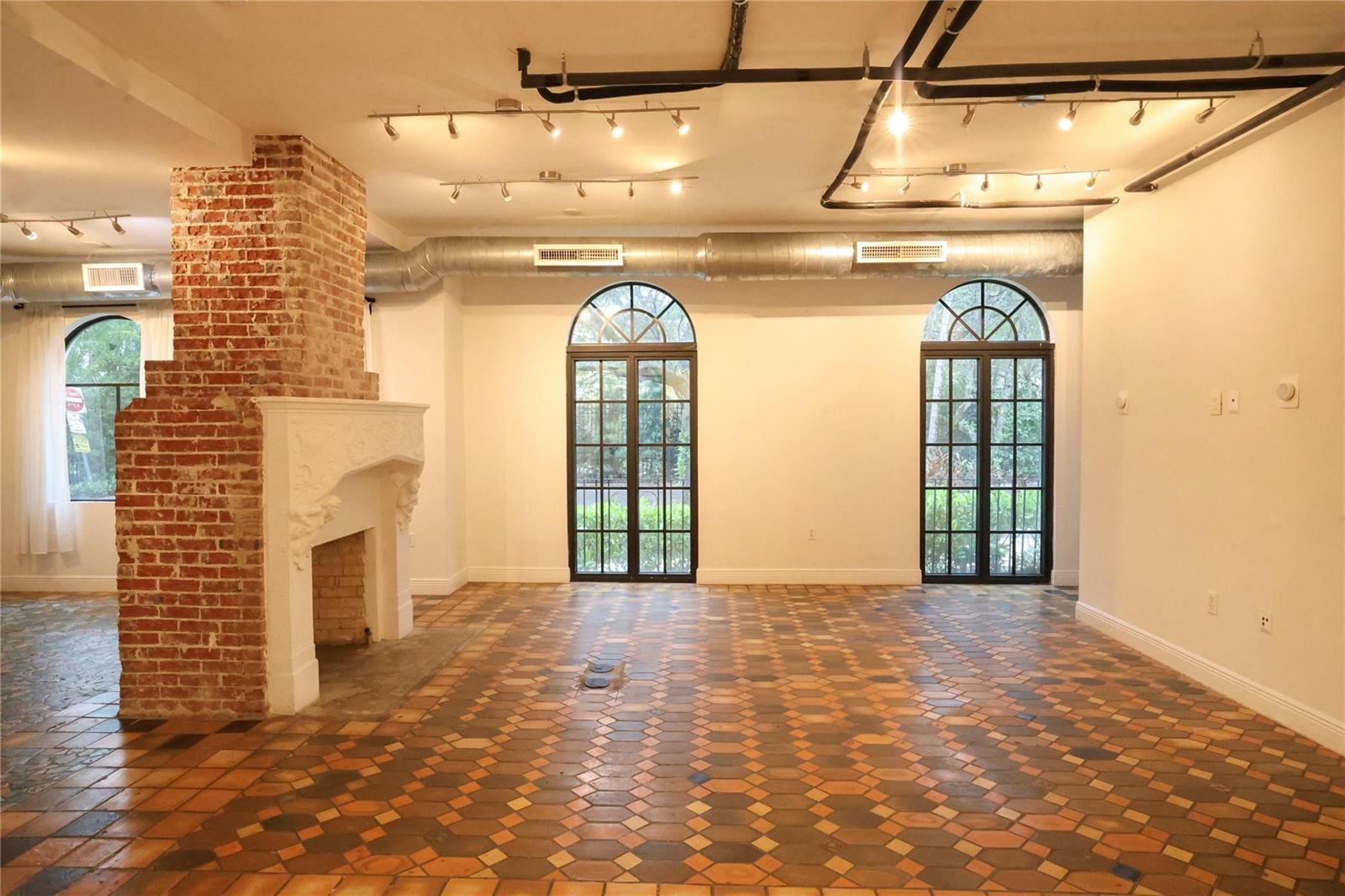 An open room features a brick fireplace, arched glass doors, and patterned tile flooring — 445 NE 56, Miami FL 33137, MIAMI, FL