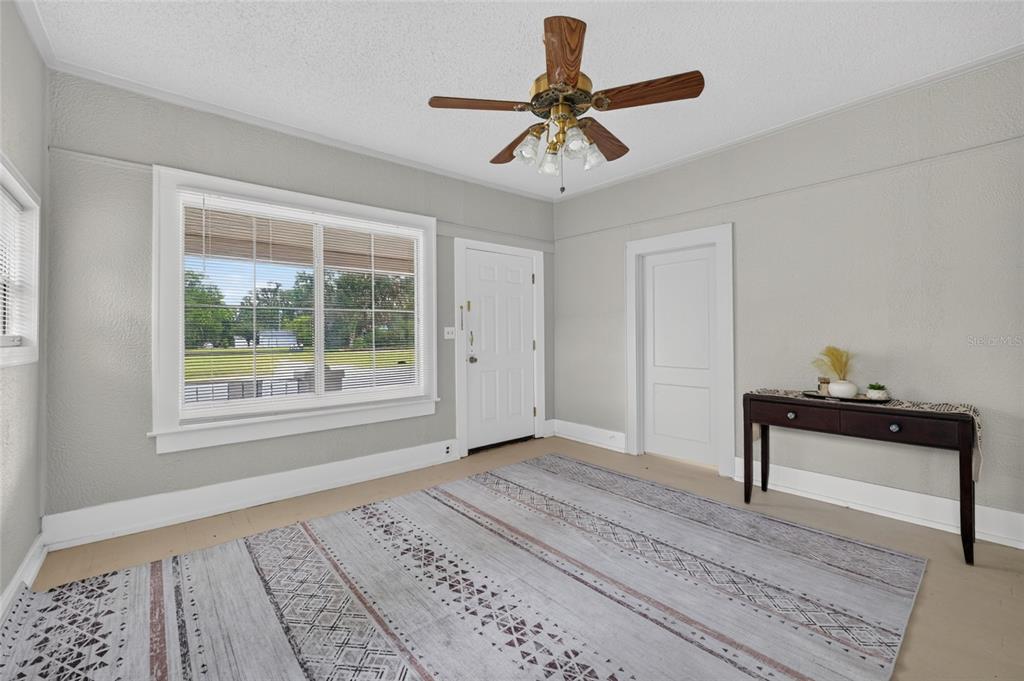 A living room features light gray walls, a ceiling fan, a large window, and a rug — 926 NE 8TH AVENUE, OCALA, FL