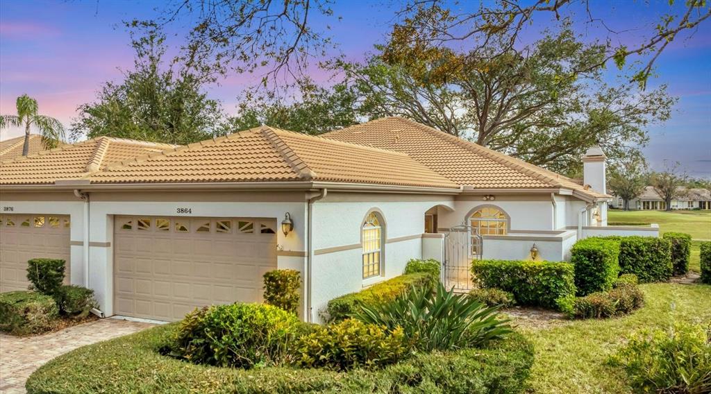 A single-story house with a tan stucco exterior, a tiled roof, and manicured landscaping — 3864 CHATSWORTH GREENE COURT UNIT 10, SARASOTA, FL