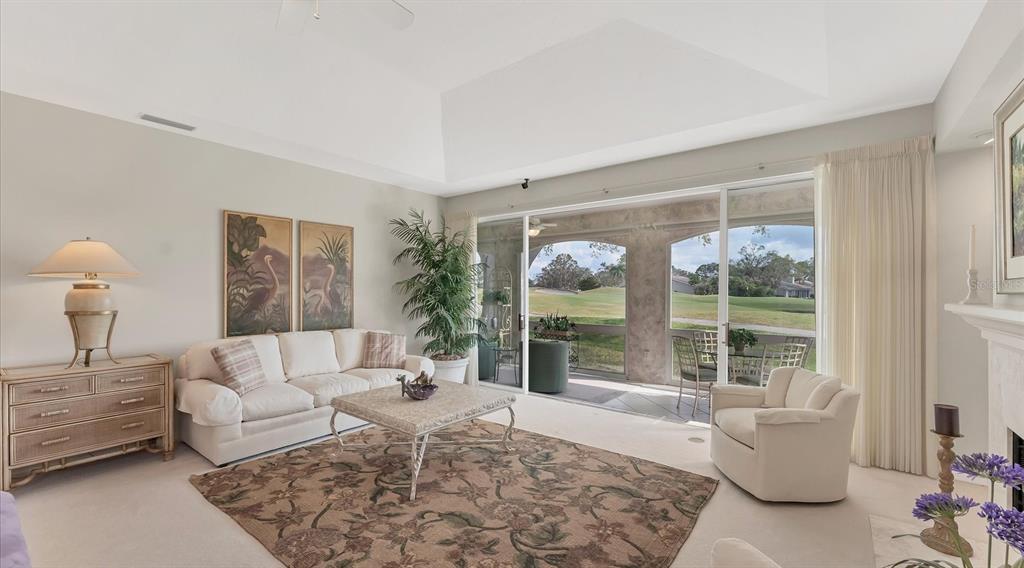 A living and dining room with a vaulted ceiling, beige carpet, and large glass sliding doors — 3864 CHATSWORTH GREENE COURT UNIT 10, SARASOTA, FL