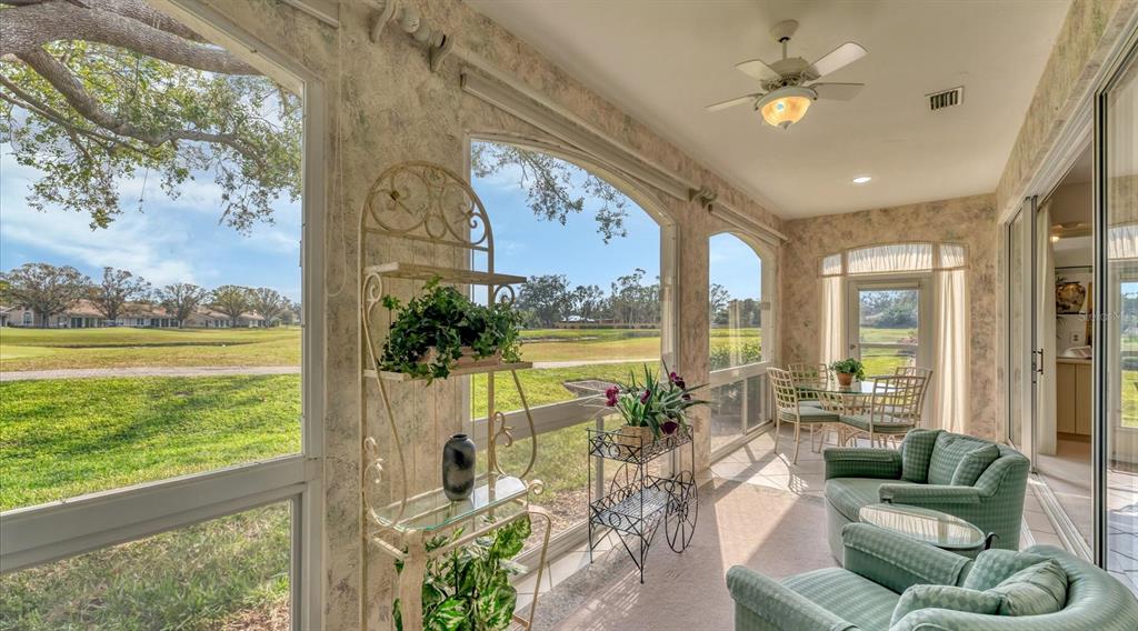 A sunroom with textured walls, tile floors, and large windows overlooking a golf course — 3864 CHATSWORTH GREENE COURT UNIT 10, SARASOTA, FL