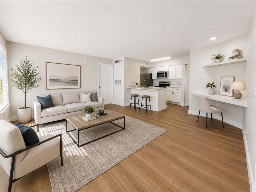 A living room with light wood flooring, a sofa, coffee table, and an open kitchen — 2217 GRAND CAYMAN COURT UNIT 1223, KISSIMMEE, FL