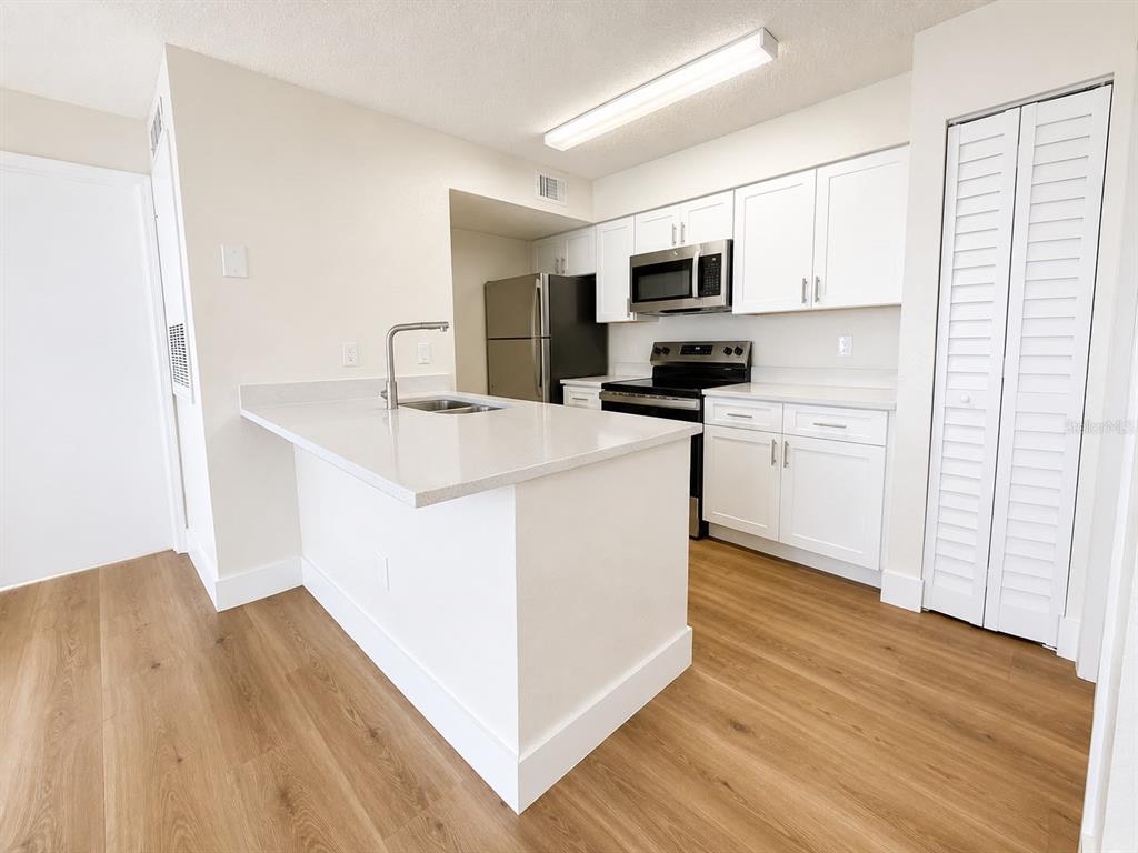 A modern kitchen features white cabinets, stainless steel appliances, and a central island with countertops — 2217 GRAND CAYMAN COURT UNIT 1223, KISSIMMEE, FL