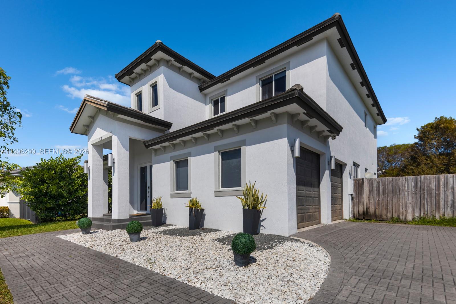 A two-story white stucco house features a paved driveway, a covered entryway, and gravel landscaping — 19781 SW 84th Ct, Cutler Bay FL 33189, CUTLER BAY, FL