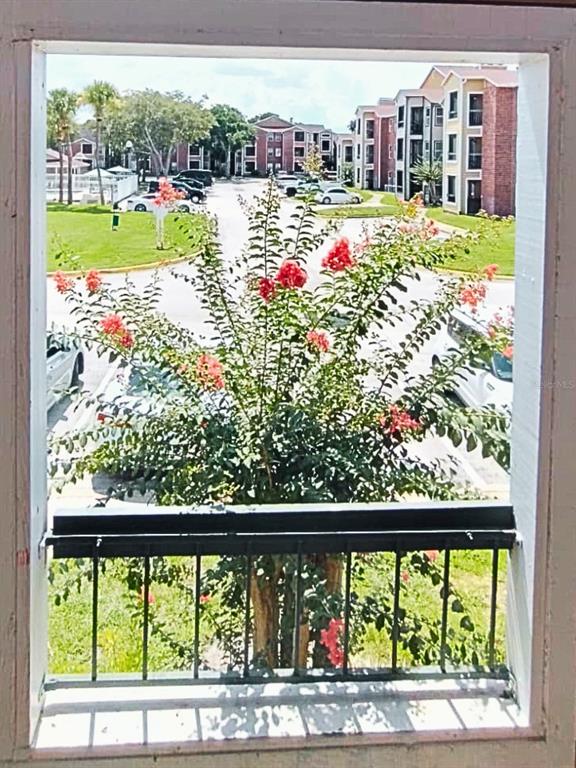 A view through a window shows a flowering crape myrtle tree in a parking lot — 4275 PERKINSHIRE LANE UNIT L204, ORLANDO, FL